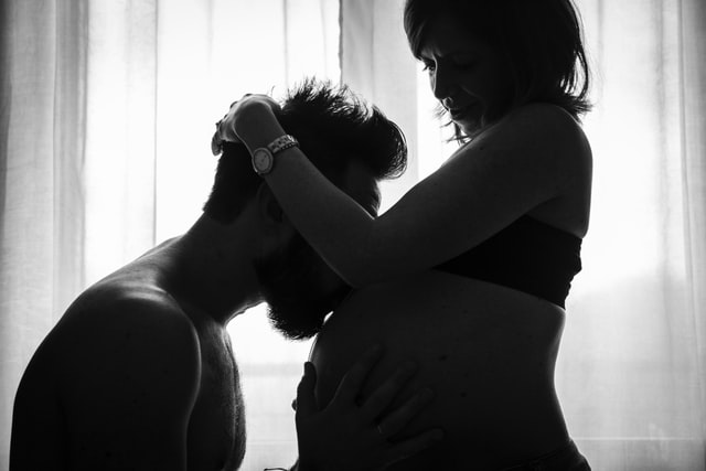 Pregnant woman, kissed on the belly by a man